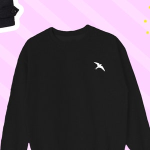 May include: A black long-sleeved sweatshirt with a white bird design on the left chest.