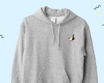 May include: A gray hooded sweatshirt with a small embroidered image of a duck on the front. The sweatshirt has a kangaroo pocket and a drawstring hood.