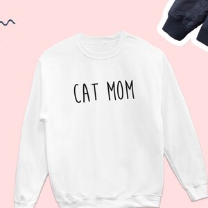 May include: White sweatshirt with the text "CAT MOM" printed in black.