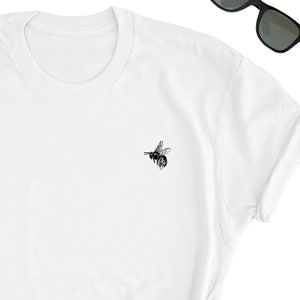 May include: White t-shirt with a black bee graphic on the front.