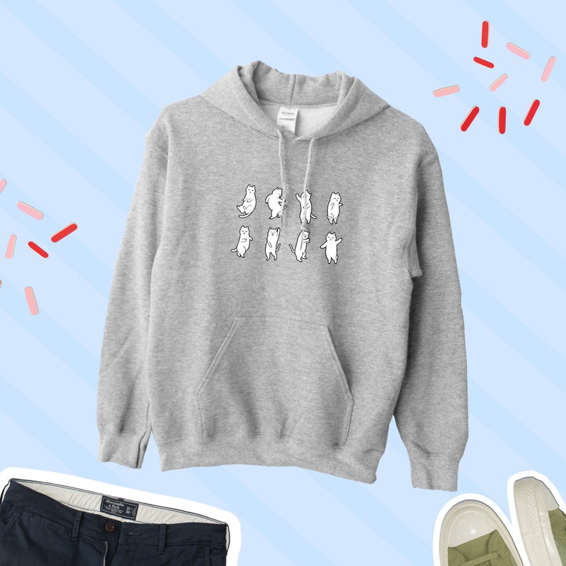 K&ouml;nnte beinhalten: Ein grauer Kapuzenpullover mit einem Aufdruck von neun tanzenden wei&szlig;en Katzen. Der Pullover hat eine K&auml;ngurutasche.