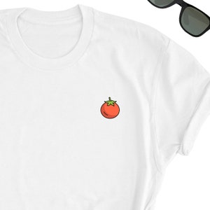May include: White t-shirt with a small red tomato graphic on the front.