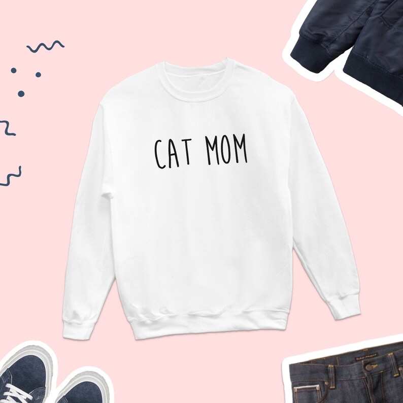 May include: White sweatshirt with the text "CAT MOM" printed in black.