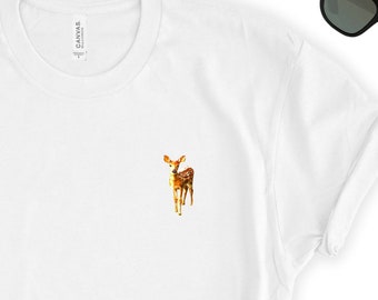 May include: White t-shirt with a small, embroidered image of a brown and white fawn standing on all four legs. The fawn is looking to the left of the image.