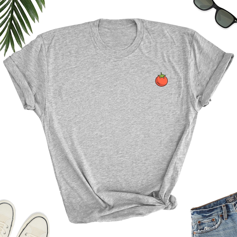 May include: A gray t-shirt with a small red tomato graphic on the left chest.