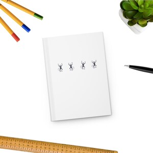 May include: A white notebook with four small black and white monkey illustrations on the front.