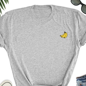 May include: A gray t-shirt with a small yellow banana graphic on the front.