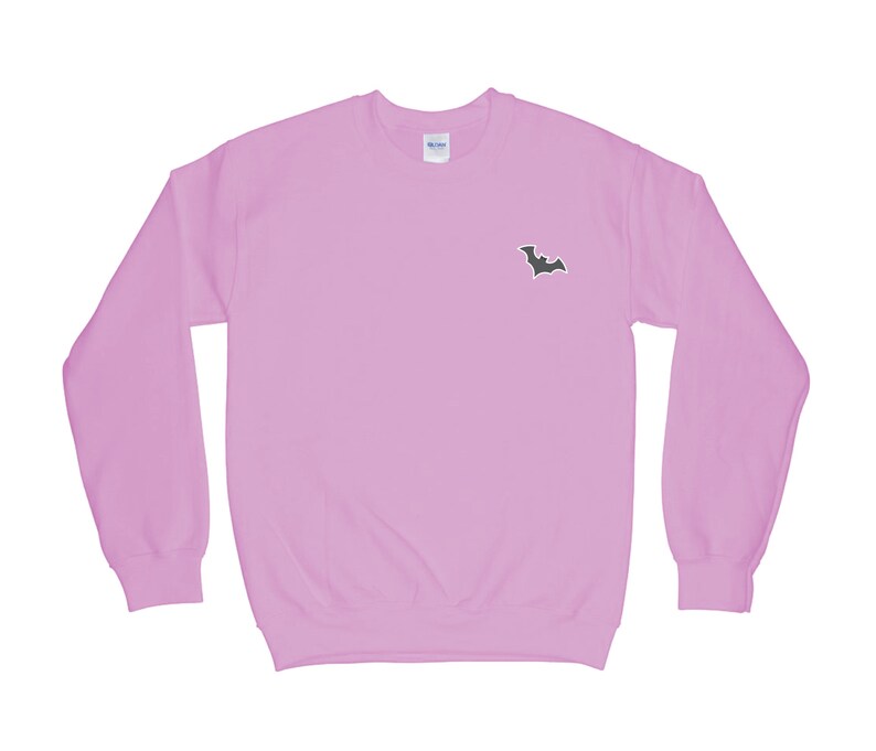May include: A light pink sweatshirt with a black bat graphic on the front.