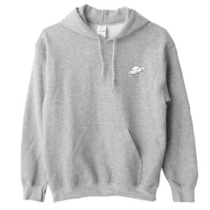 K&ouml;nnte beinhalten: Ein grauer Kapuzenpullover mit einer kleinen schwarzen und wei&szlig;en UFO-Grafik auf der Vorderseite.