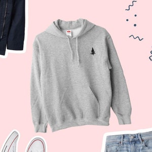 May include: A gray hooded sweatshirt with a small black tree design on the front. The sweatshirt has a kangaroo pocket and a drawstring hood.