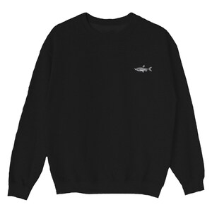 K&ouml;nnte beinhalten: Ein schwarzer Pullover mit einem kleinen gestickten Fischdesign auf der linken Brust.