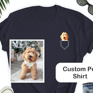 May include: Navy blue t-shirt with a custom pet design. The shirt features a pocket design with a dog's face and a framed photo of the dog. The text "Custom Pet Shirt" is displayed on the shirt. Sunglasses are placed on the top right.