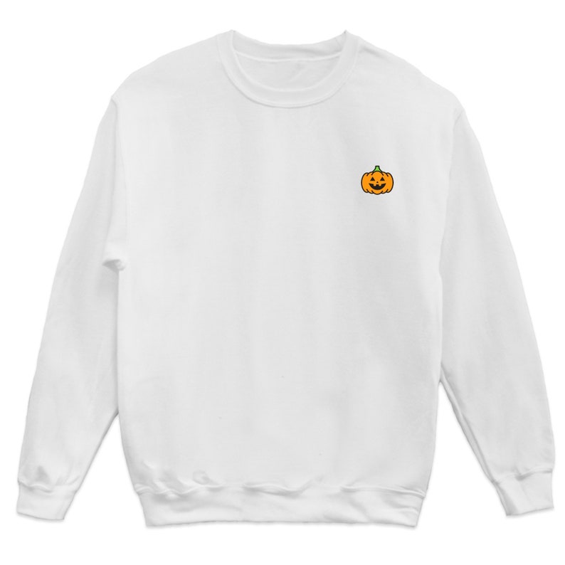 Puede incluir: Sudadera blanca de manga larga con una peque&ntilde;a calabaza naranja con una cara de calabaza tallada bordada en el pecho izquierdo.