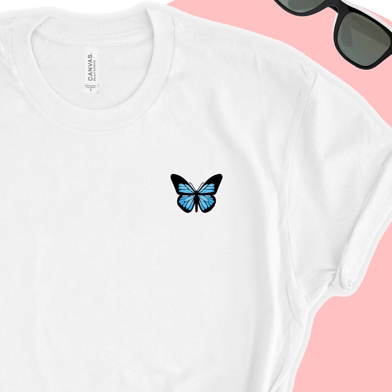 May include: White t-shirt with a blue butterfly graphic on the front.