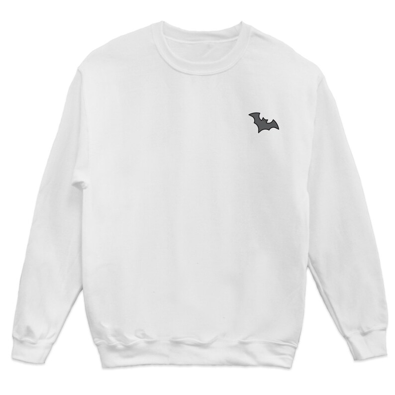 May include: White long-sleeved sweatshirt with a small black bat graphic on the left chest.