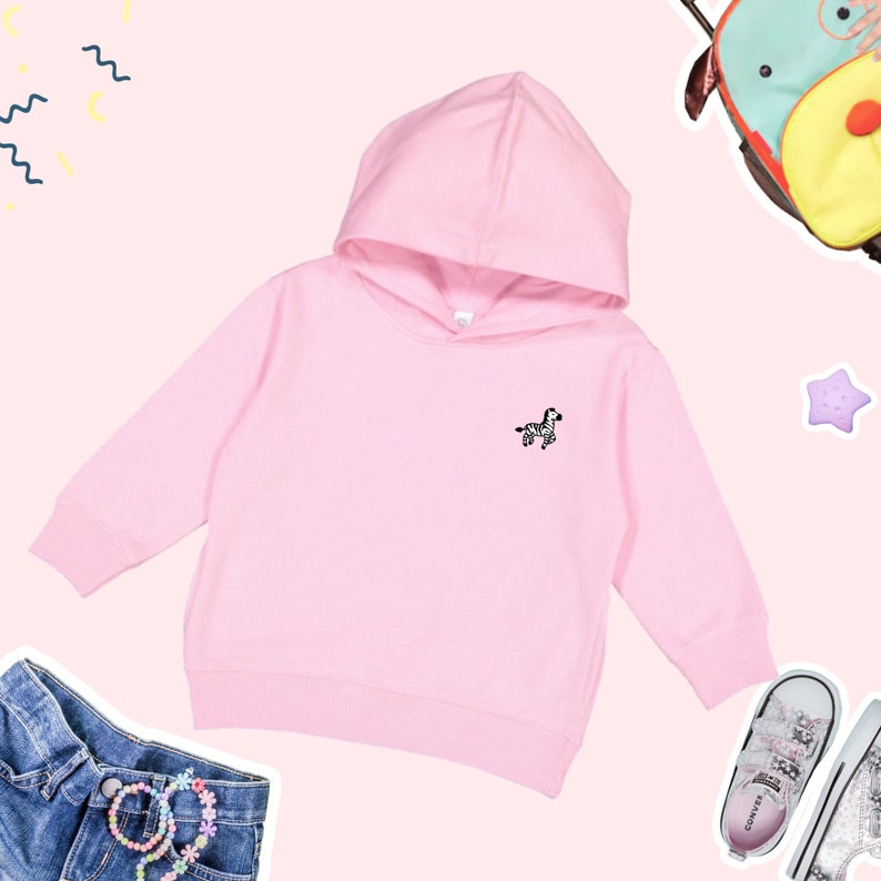 May include: A pink hooded sweatshirt with a small zebra graphic on the front. The sweatshirt has long sleeves and a kangaroo pocket.