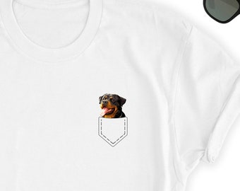 May include: White t-shirt with a black and brown Rottweiler dog peeking out of a pocket on the front of the shirt.