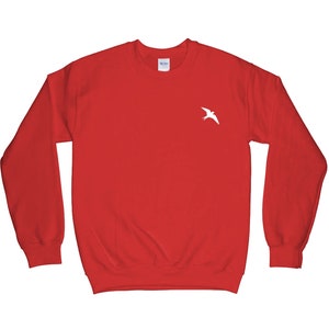 May include: Red sweatshirt with a white bird graphic on the front.