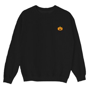 Puede incluir: Sudadera negra con una peque&ntilde;a calabaza naranja con una cara de calabaza tallada bordada en el pecho izquierdo.