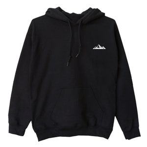 Op de afbeelding: Zwarte hoodie met een witte bergafbeelding op de linkerborst. De sweatshirt heeft een voorzak en een capuchon met trekkoord. De stof lijkt zacht en comfortabel.