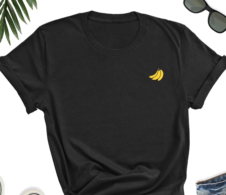 May include: A black t-shirt with a small yellow embroidered design of three bananas on the left chest.