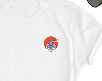 May include: White t-shirt featuring a red circle with a graphic of a bowl of noodles and chopsticks. The text "麺" is below the bowl.