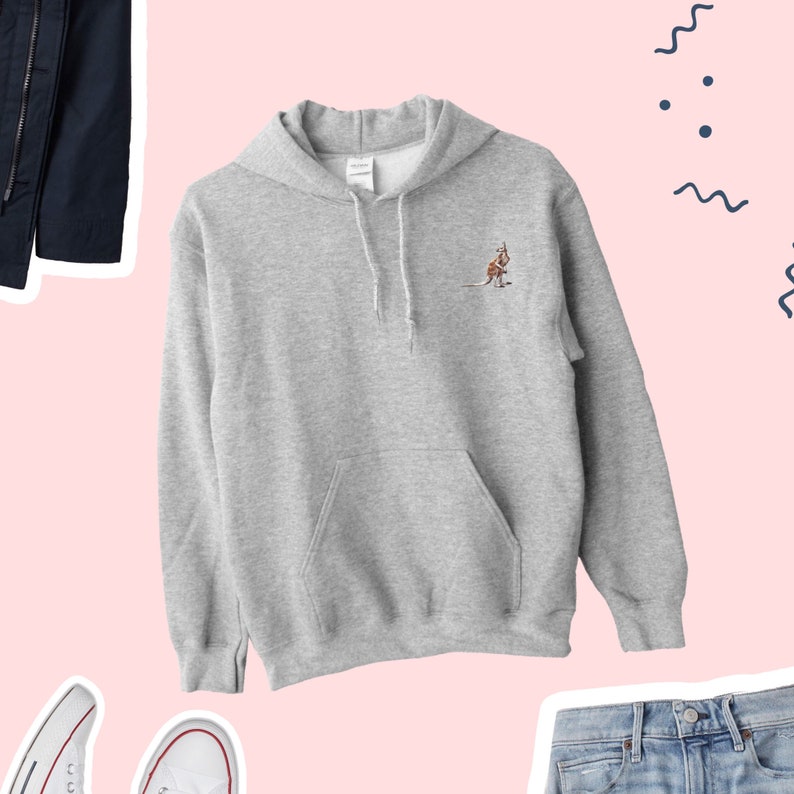 May include: A grey hoodie featuring a kangaroo design. The hoodie has a drawstring hood and a front pocket. The kangaroo is embroidered in brown and tan. The hoodie is made of a soft, comfortable material. The hoodie is a casual style.
