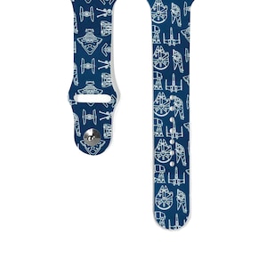 Op de afbeelding: Een blauwe Apple Watch band met een wit patroon van Star Wars ruimteschepen en de Millennium Falcon.