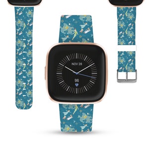 May include: A rose gold smartwatch with a blue and white patterned band featuring characters from the Disney movie Peter Pan. The watch face displays the date "NOV 28" and the time. The heart rate is displayed as "96".