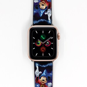 Op de afbeelding: Een gouden Apple Watch met een zwart display en een Mickey Mouse Tovenaarsleerling-thema horlogeband. De band heeft een blauwe achtergrond met sterren en Mickey Mouse in zijn tovenaarshoed en -gewaad.