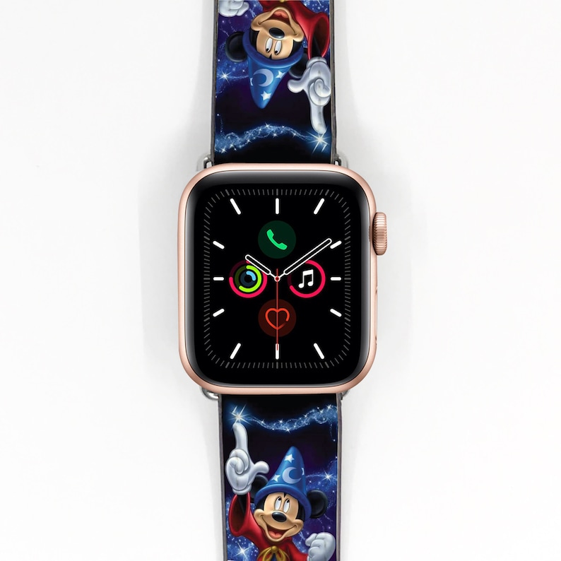 Op de afbeelding: Een gouden Apple Watch met een zwart display en een Mickey Mouse Tovenaarsleerling-thema horlogeband. De band heeft een blauwe achtergrond met sterren en Mickey Mouse in zijn tovenaarshoed en -gewaad.