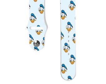 Puede incluir: Una banda de reloj Apple blanca con un fondo azul claro y un patrón repetido de la cara de Donald Duck.