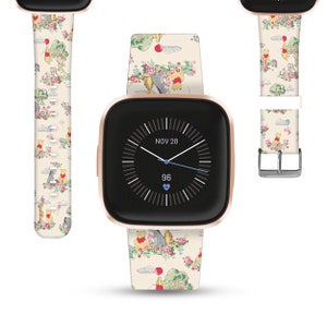 Könnte beinhalten: Eine roségoldene Smartwatch mit einem weißen Armband mit einem Winnie-the-Pooh-Muster. Das Zifferblatt der Uhr zeigt das Datum "NOV 28" und die Uhrzeit 96 an.
