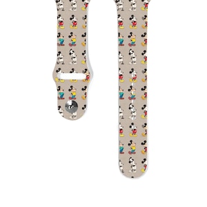 May include: A beige Apple Watch band with a repeating pattern of Mickey Mouse in various poses. The band is made of silicone and has a white buckle.