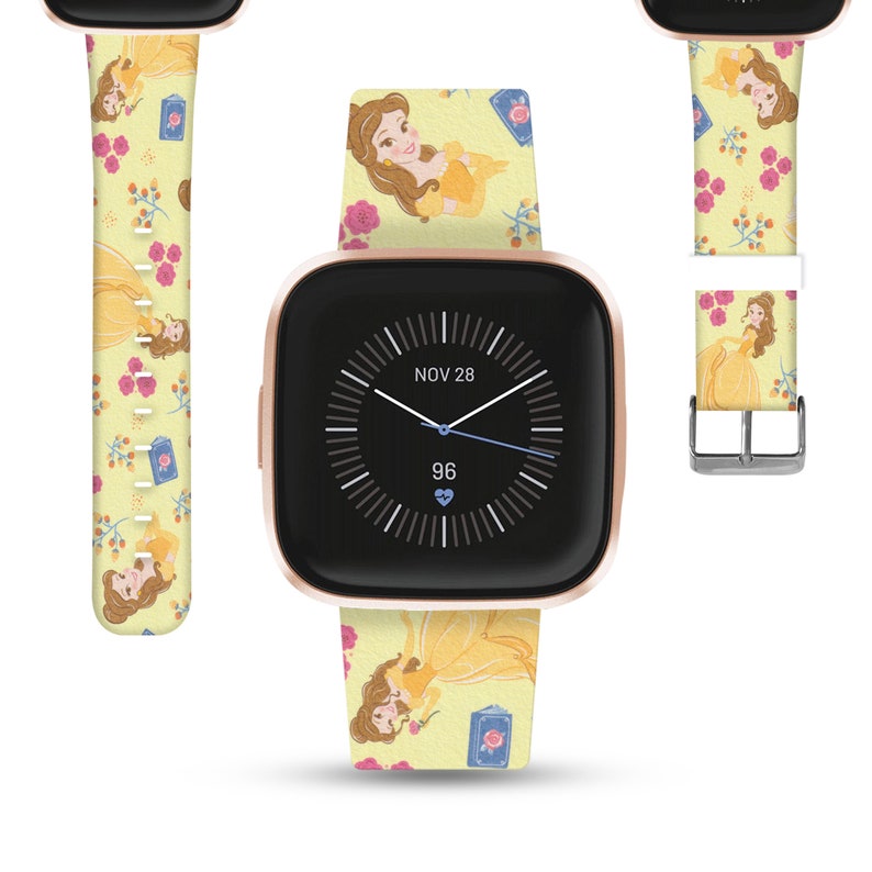 K&ouml;nnte beinhalten: Eine goldfarbene Smartwatch mit einem gelben und rosafarbenen Armband mit Belle aus Disneys Die Sch&ouml;ne und das Biest. Das Zifferblatt der Uhr zeigt das Datum "NOV 28" und die Uhrzeit 96.