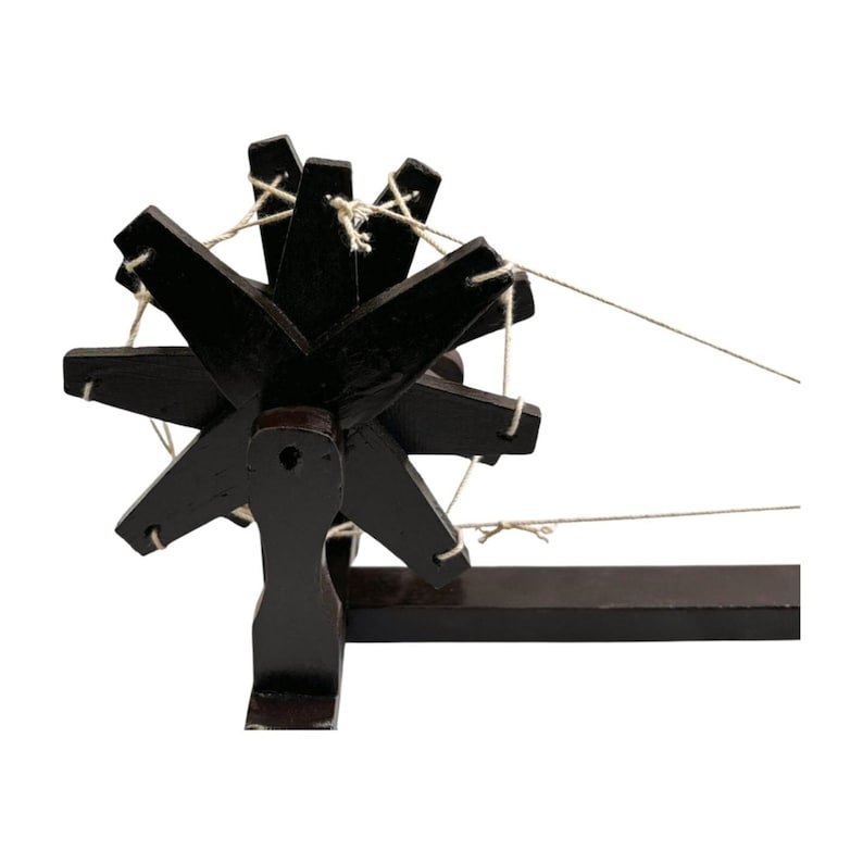 Close up of dark spokes and wood grain on a handcrafted Gandhi charkha spinning wheel, rustic feel.