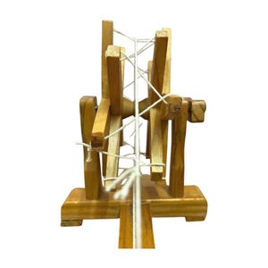 Rear angle showing thread tension and upright supports on a wood Gandhi charkha spinning wheel, decor piece.