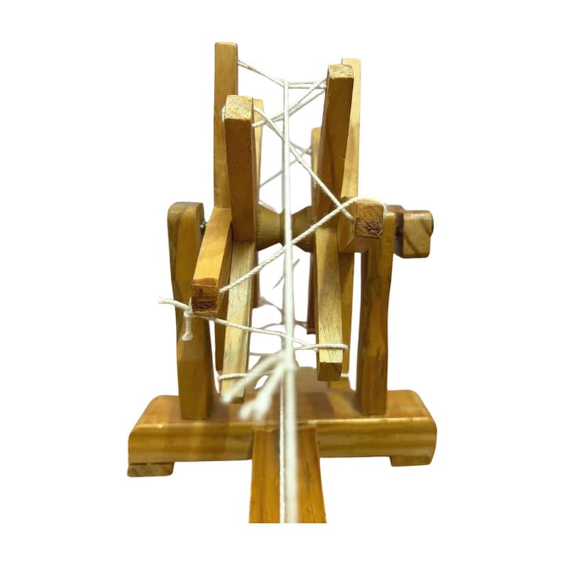 Rear angle showing thread tension and upright supports on a wood Gandhi charkha spinning wheel, decor piece.