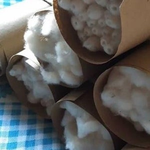 May include: Several brown cardboard tubes filled with white cotton fiber. The tubes are stacked on top of each other on a blue and white checkered surface.