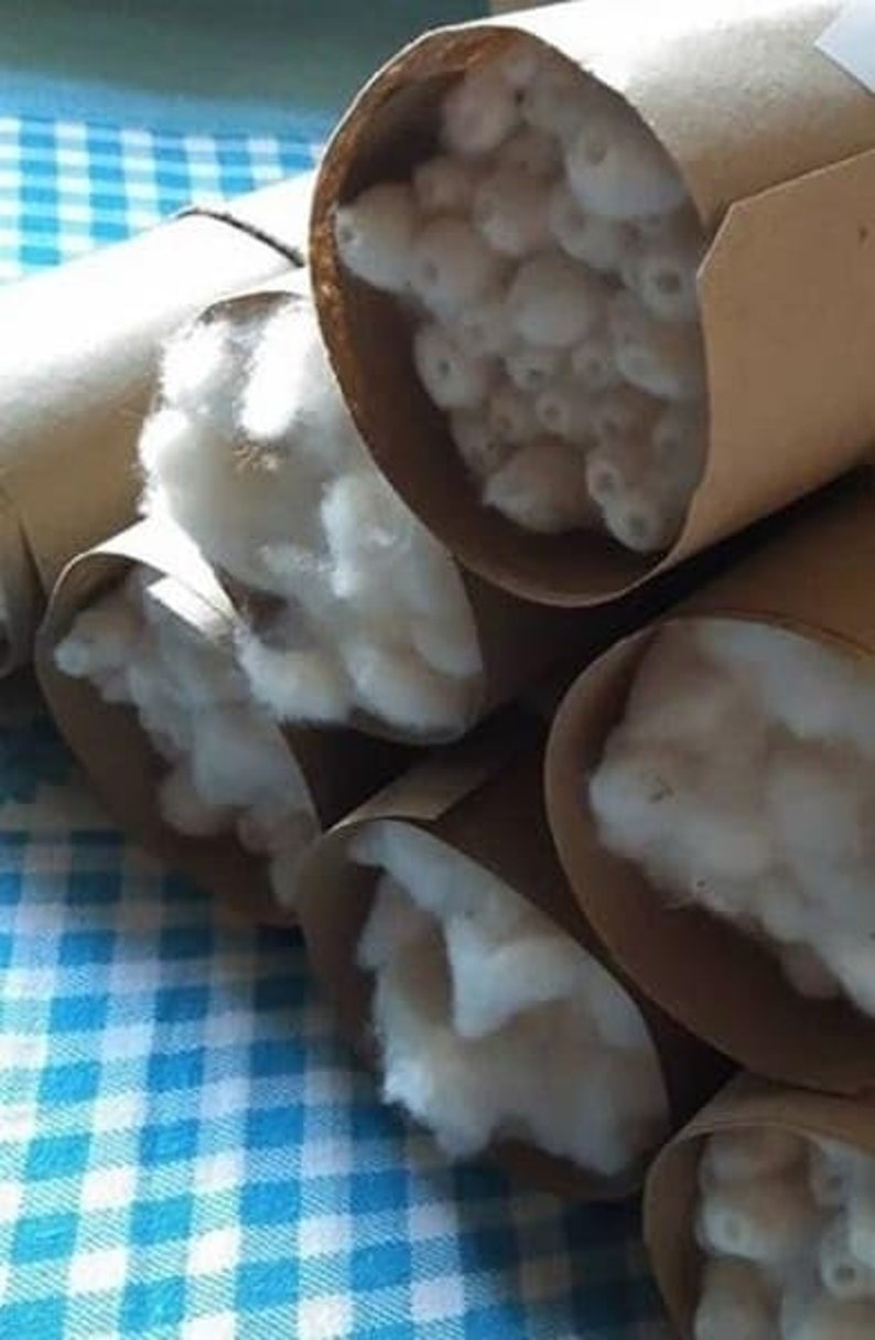 May include: Several brown cardboard tubes filled with white cotton fiber. The tubes are stacked on top of each other on a blue and white checkered surface.