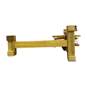 Low side shot focusing on base and connectors of the portable Gandhi charkha spinning wheel, work-ready display.