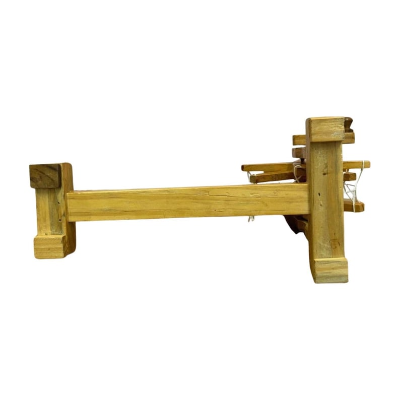 Low side shot focusing on base and connectors of the portable Gandhi charkha spinning wheel, work-ready display.