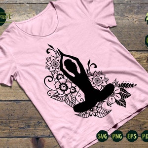 May include: A black silhouette of a person in a yoga pose surrounded by intricate floral designs. The design is on a pink t-shirt. The words "SVG PNG EPS PDF DXF" are visible at the bottom of the image.