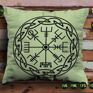 May include: A green throw pillow with a black and white compass design. The compass is surrounded by a circular knot pattern.