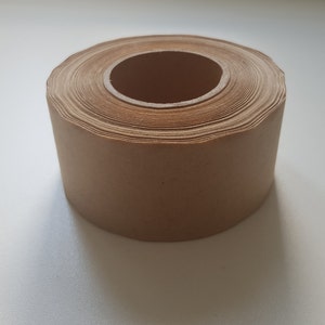 Op de afbeelding: Een rol bruin papiertape, strak gewikkeld op een kartonnen kern.