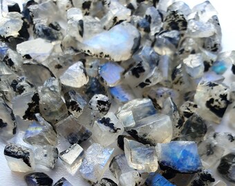 May include: A collection of iridescent rainbow moonstone rough, with black inclusions, in various shapes and sizes.
