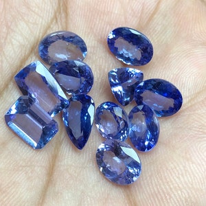 May include: A collection of ten faceted gemstones in various shapes and sizes. The gemstones are a deep blue color and have a high shine.