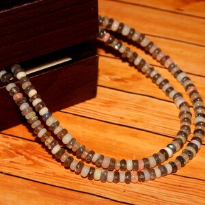 May include: A double strand necklace made of iridescent grey and white beads. The necklace is made of natural stones and is a beautiful piece of jewelry.