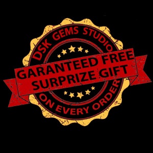 May include: A black background with a distressed, circular emblem. The emblem features the text "DSK GEMS STUDIO" in a circular pattern, with a red banner reading "GUARANTEED FREE SURPRIZE GIFT ON EVERY ORDER". Gold stars and a yellow border complete the design.