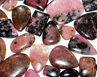 May include: A collection of pink and black gemstone cabochons. The stones are smooth and polished, with a variety of shapes and sizes.